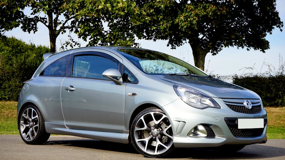 Silver hatchback car parked on a sunny day with trees in the background