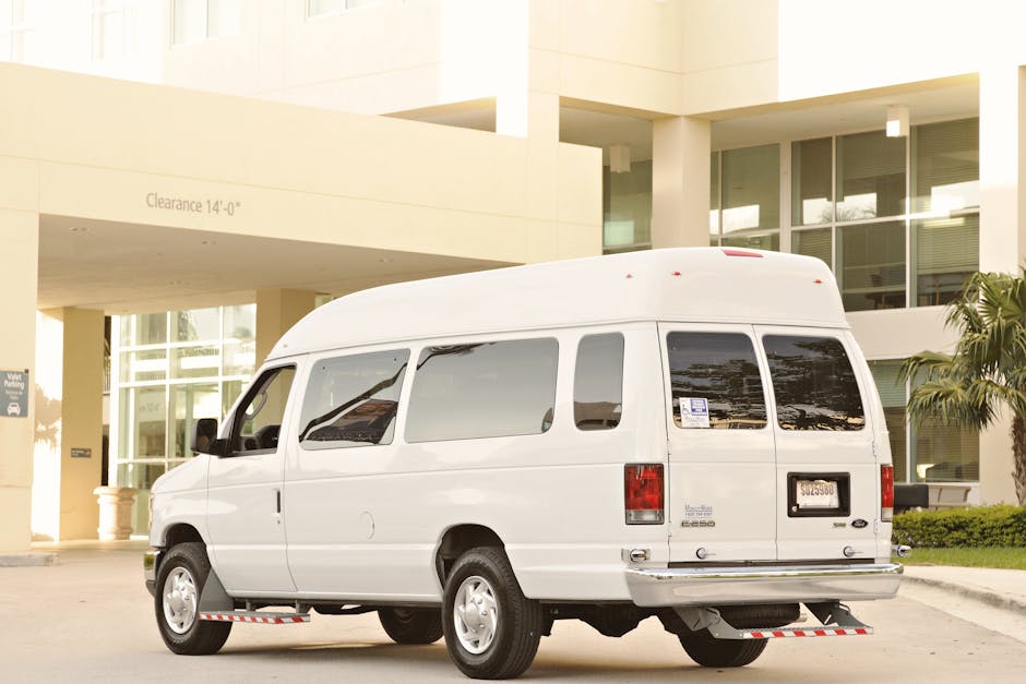 White passenger van parked outside a modern building under a clearance sign.
