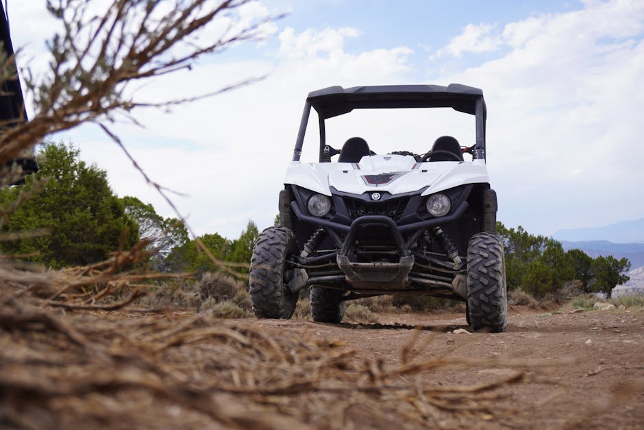 White off-road utility vehicle conquering rugged terrain outdoors under a bright sky